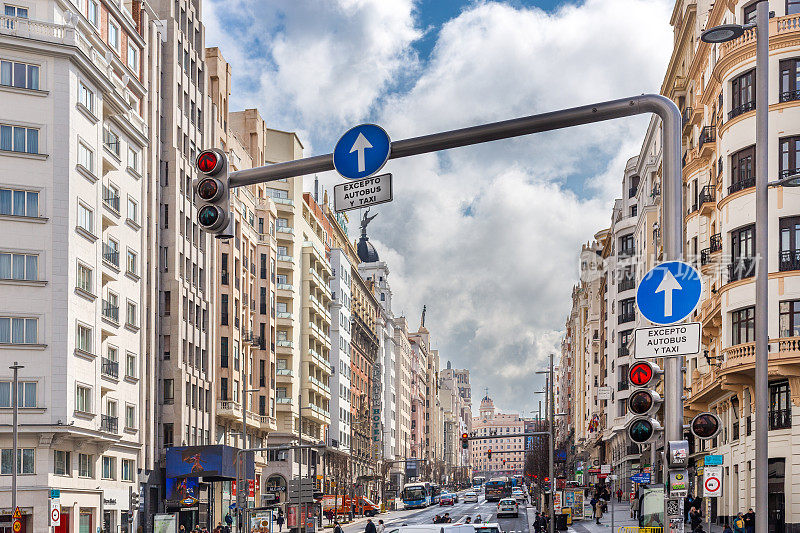 马德里gran vía街的建筑和交通。中午有云，天气晴朗